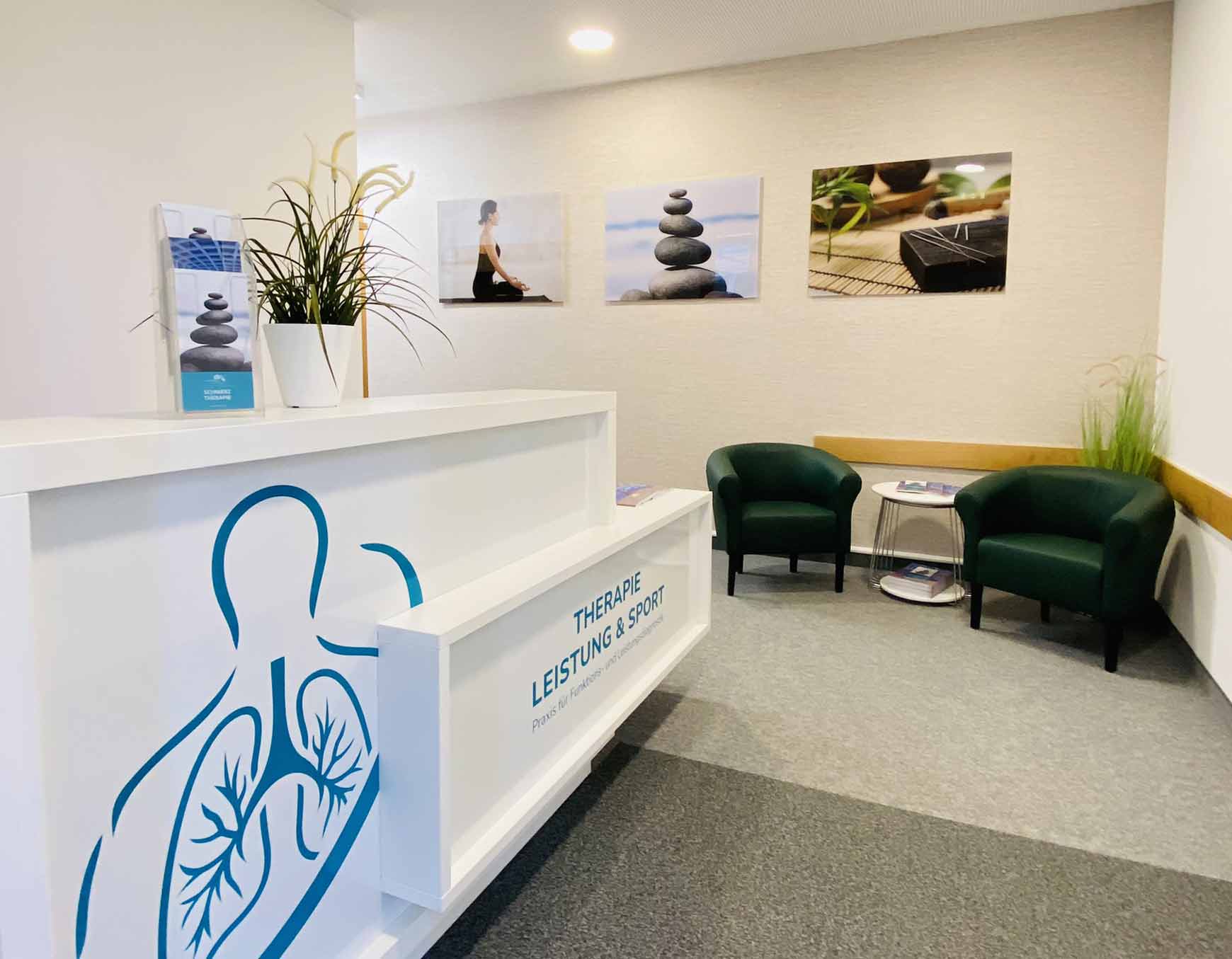 Zu sehen ist der Eingangsbereich der Arztpraxis an der SaarowTherme. Links vom Eingang befindet sich ein weißer Tresen mit Türkisfarbener Aufschrift "Therapie Leistung &Sport". Auf dem Tresen befindet eine kleine Grünpflanze und ein Prospektständer. Im Hintergrund befinden sich zwei dunkel grüne Sessel mit einem weißen, runden Couchtisch. Auf diesem befinden sich weitere Prospekte. Dekorativ ist der Eingangs Bereich mit einer Stehgrünpflanze und drei Bildern versehen. Hellgrauer Teppich, Cremefarbene Wand.