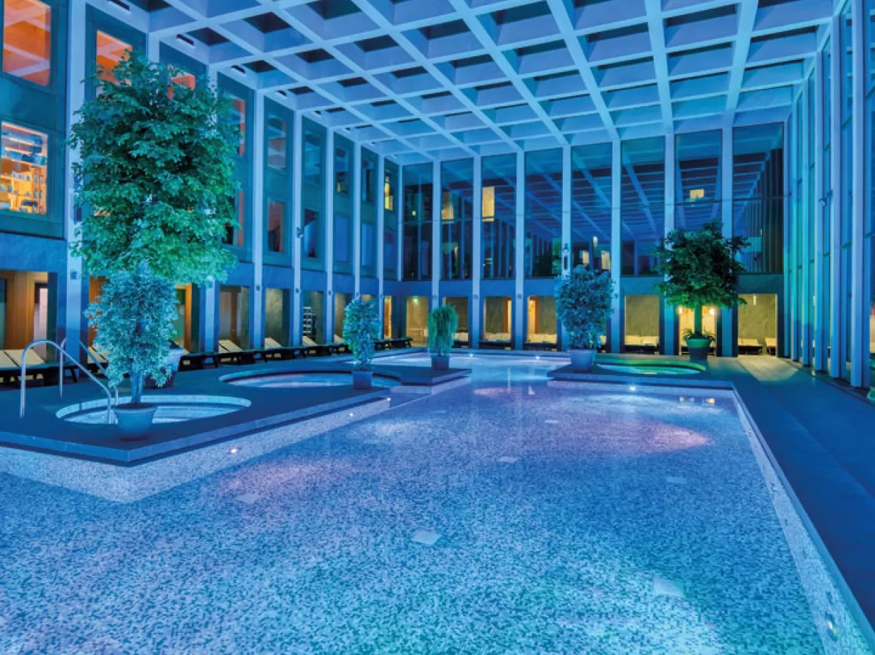 Das Thermalbad der SaarowTherme mit Abendbeleuchtung. Blaues Licht und beleuchtete Becken tauchen das Thermalbad in einer romantischen Atmosphäre.