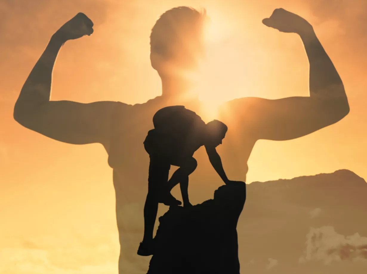 Aufnahme eines Mannes, der an die Spitze eines Berges angekommen ist. Er hat den Berg erfolgreich bestiegen und im Hintergrund scheint die Sonne. Im Vordergrund ist abgebildet wie sein Schatten vor lauter Freude die Arme seitlich hochhält und dabei seine Muskeln anspannt.