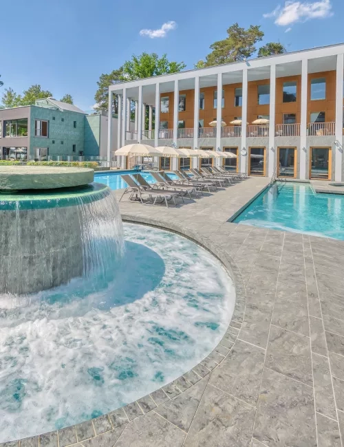 Massagepilz mit Strömungskanal im Außenbereich der SaarowTherme. Türkisblauem Wasser, blauer Himmel und Liegen am Beckenrand vermitteln Urlaubsfeeling pur.