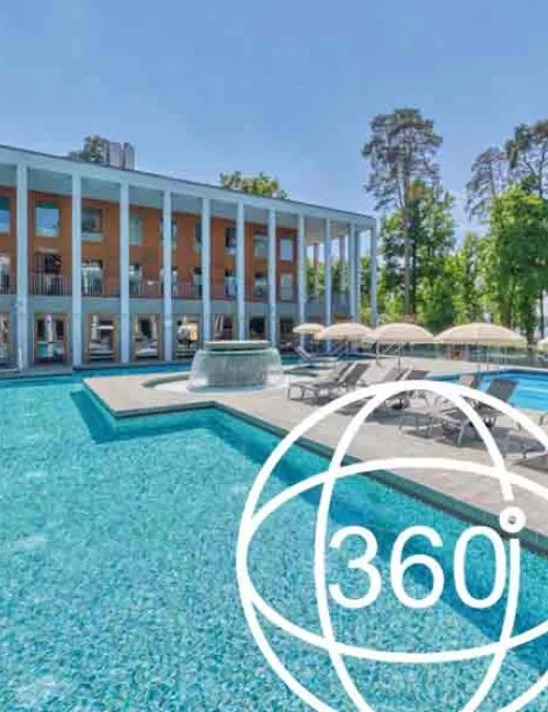 Außenbereich des Thermalsolebeckens  SaarowTherme am Tag mit plätschernden Strömungskanal, graue Liegen mit weißen aufgespannten Sonnenschirmen. Im Hintergrund ein Teil des Hauptgebäudes mit hellbrauner Gebäudefront und weißen Säulen im Vordergrund. Strahlend blauer Himmel. Dreihundertsechzig Grad als Zahl und ein Kreis ist abgebildet.