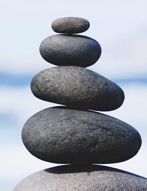 Bild von dunkelgrauen Steinen die in einer Linie gestapelt sind als Steinmännchen.