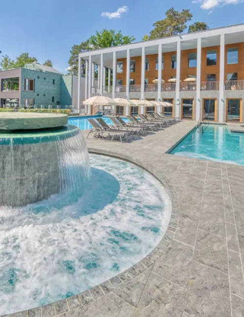 Massagepilz mit Strömungskanal im Außenbereich der SaarowTherme. Türkisblauem Wasser, blauer Himmel und Liegen am Beckenrand vermitteln Urlaubsfeeling pur.