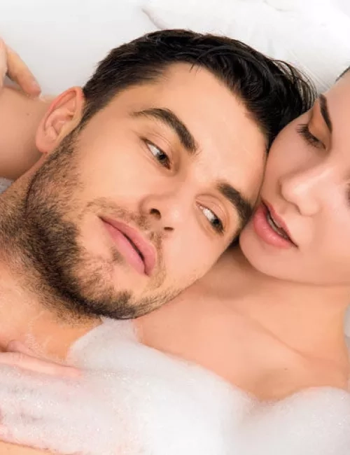 Ein Paar entspannt gemeinsam in einer mit Schaum gefüllten Badewanne und genießt die Nähe zueinander.