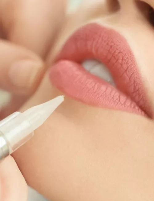 Ein Lippenpflegeprodukt wird mit einem feinen Stift auf die Lippen aufgetragen.