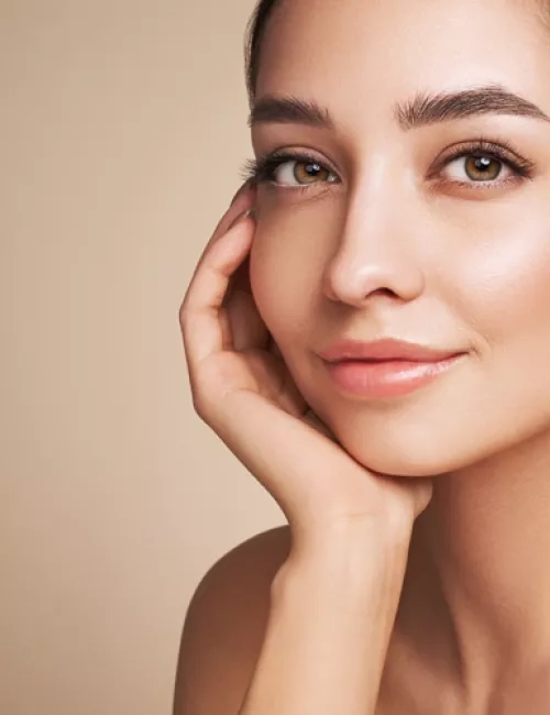 Porträt einer Frau mit der Hand an der Wange und leichtem Lächeln.