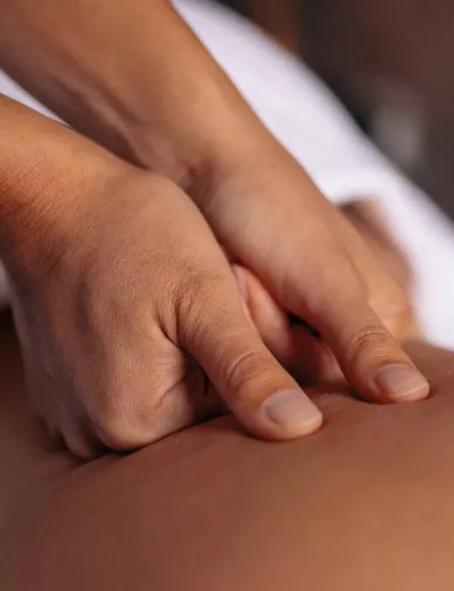 Nahaufnahme einer intensiven Rückenmassage, bei der mit den Daumen Druck ausgeübt wird.