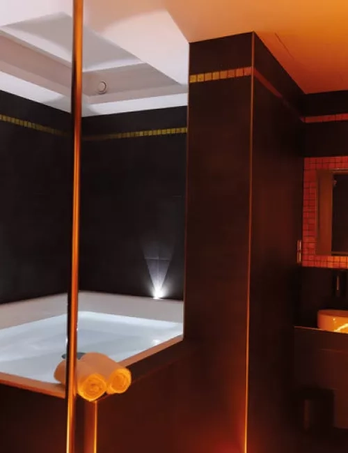 Modern gestaltender Floatingraum in SaarowTherme mit großer Floating-Wanne, beleuchtetem Spiegel über einem Waschbecken und einem aufgehängten Bademantel. Stimmungsvolle Lichtakzente schaffen eine entspannte Atmosphäre.