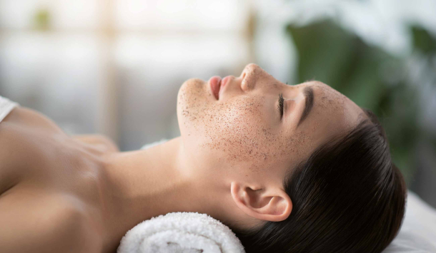 Frau liegt entspannt mit geschlossenen Augen auf dem Rücken, ein weiches Handtuch stützt ihren Kopf. Die Umgebung wirkt ruhig und hell.