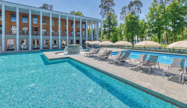 Außenbereich der SaarowTherme mit Thermalsolebecken, Strömungskanal und Sonnenliegen. Entspannende Atmosphäre unter blauem Himmel.