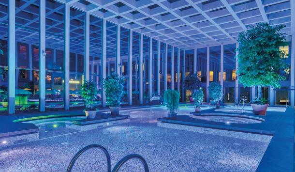 Das Thermalbad der SaarowTherme mit Abendbeleuchtung. Blaues Licht und beleuchtete Becken tauchen das Thermalbad in einer romantischen Atmosphäre.