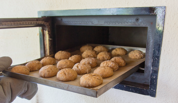 Blech mit frisch gebackenen Brötchen wird aus dem Ofen gezogen
