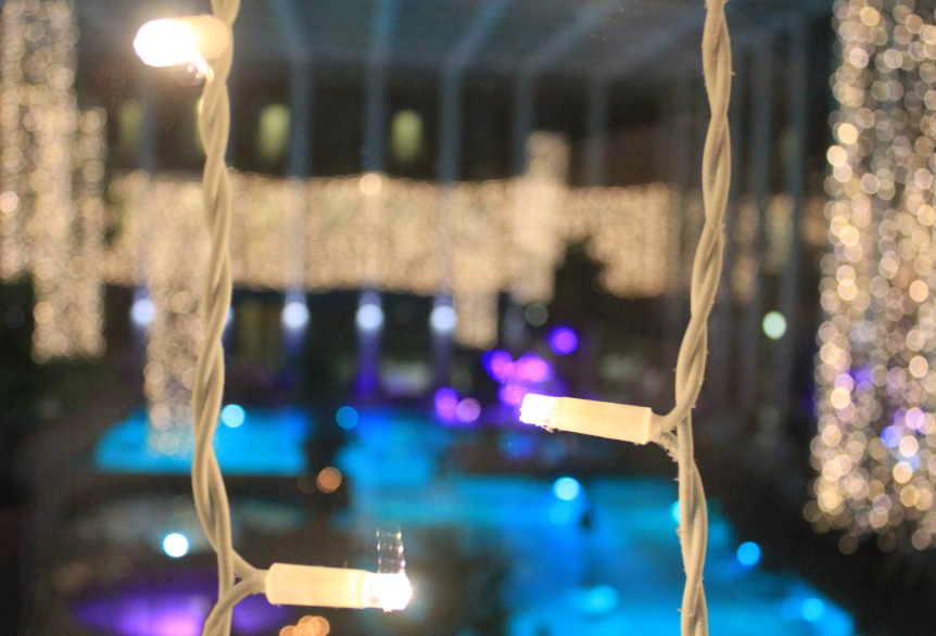 Das Innenbecken der SaarowTherme wird blau mit lila Farbtupfern beleuchtet und die warm-weißen Lichterketten, hängend von der Decke, ergeben eine gemütliche Atmosphäre am Abend. 