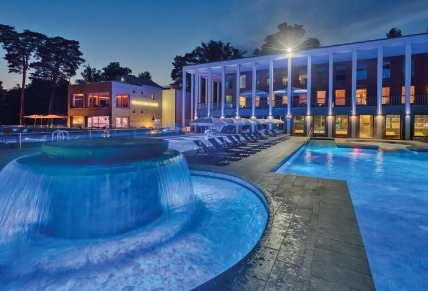 Massagepilz mit Strömungskanal im Außenbereich der SaarowTherme. Türkisblauem Wasser, sternenklarer Nachthimmel und Liegen am Beckenrand vermitteln eine entspannte Abendliche Atmosphäre.