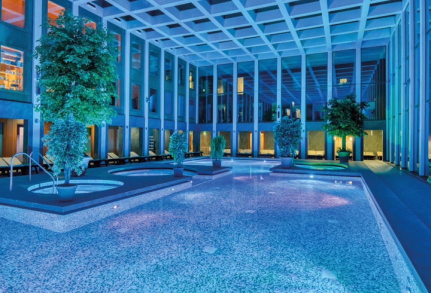 Das Thermalbad der SaarowTherme mit Abendbeleuchtung. Blaues Licht und beleuchtete Becken tauchen das Thermalbad in einer romantischen Atmosphäre.