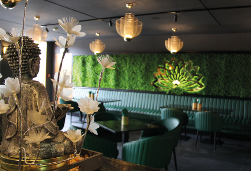 Asiatisches Restaurant in der Therme. Modern Eingerichtet mit bequemen Möbel und Asiatische Dekorationen. Im Hintergrund befindt sich eine Wand mit künstlichem Moos und eine Goldene Lotusblume mit indirekter Belechtung.
