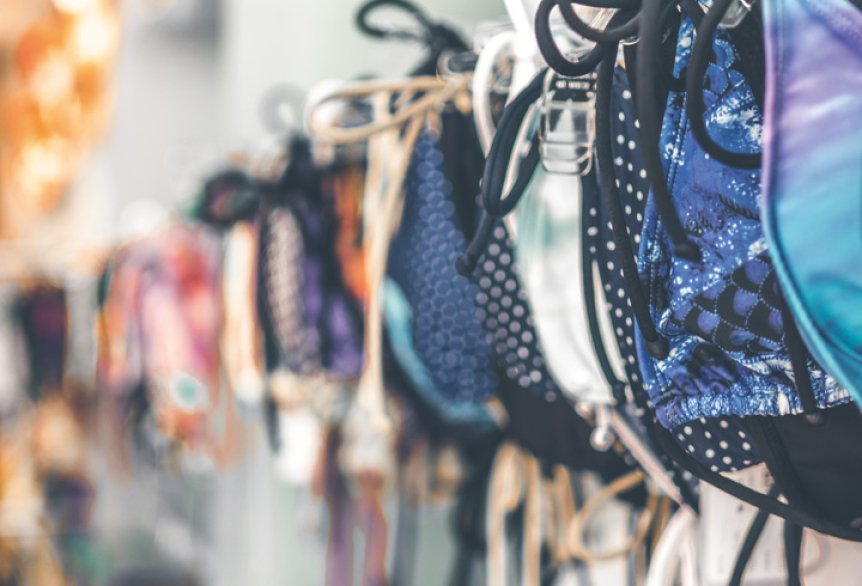 Bunte Bikinis hängend in einer Reihe auf Kleiderbügel. 