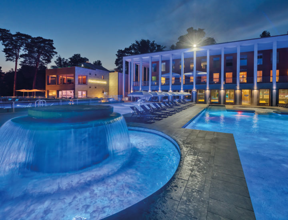 Massagepilz mit Strömungskanal im Außenbereich der SaarowTherme. Türkisblauem Wasser, sternenklarer Nachthimmel und Liegen am Beckenrand vermitteln eine entspannte Abendliche Atmosphäre.