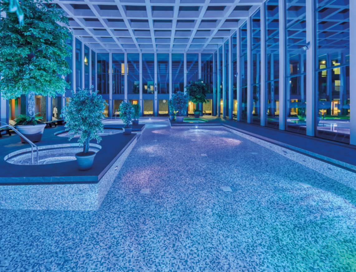 Das Thermalbad der SaarowTherme mit Abendbeleuchtung. Blaues Licht und beleuchtete Becken tauchen das Thermalbad in einer romantischen Atmosphäre.