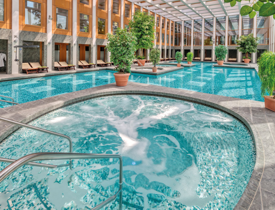 Thermalbad mit großem Whirlpool im Innenbereich. Sprudelndes Wasser im Whirlpool und türkisblauem Wasser im Thermalbad bieten Raum zur Entspannung.