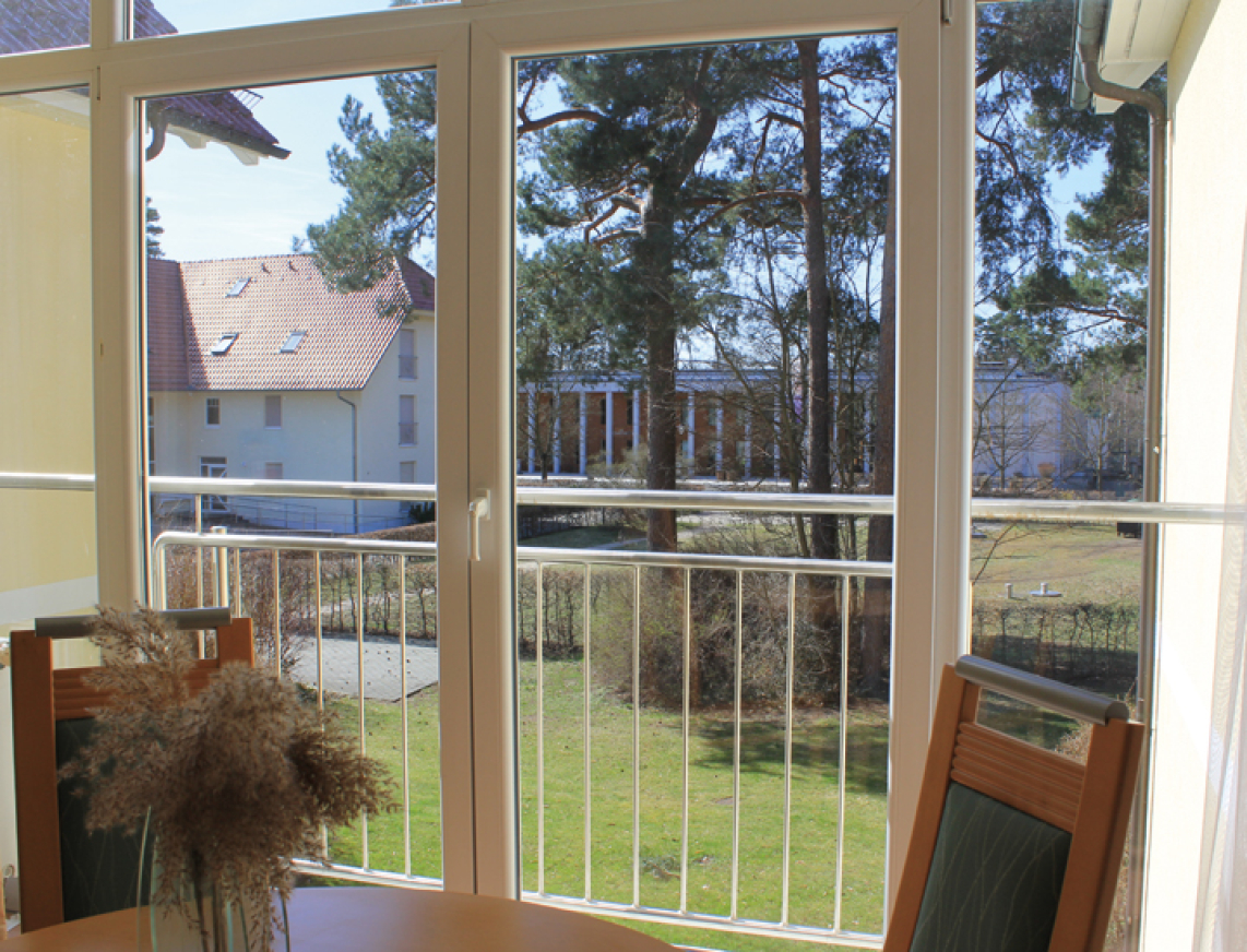 Ausblick aus der Ferienwohnung an der SaarowTherme. Aus einem großen Balkonfenster blickt man direkt auf das Gebäude der SaarowTherme.