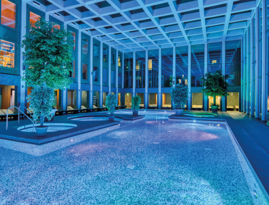 Das Thermalbad der SaarowTherme mit Abendbeleuchtung. Blaues Licht und beleuchtete Becken tauchen das Thermalbad in einer romantischen Atmosphäre.